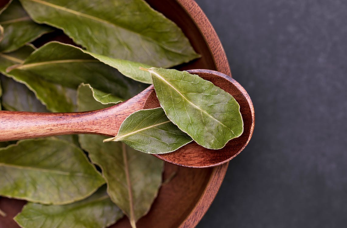 bay leaves on a bowl and a wooden spoon