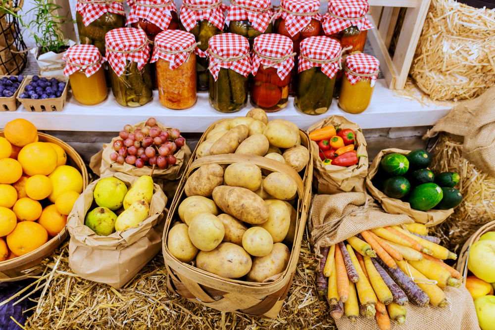 Vibrant display of fresh fruits, vegetables, jars of homemade preserves at farmers market in lively setting