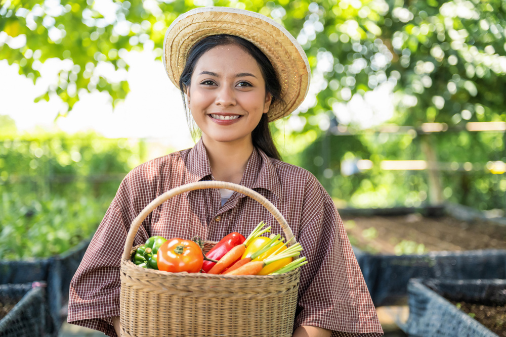 Portrait of smiling teenager female farmer holding fresh vegetables proudly showing healthy vegetables from garden, Self-sufficient lifestyle with homegrown crops in backyard harvest