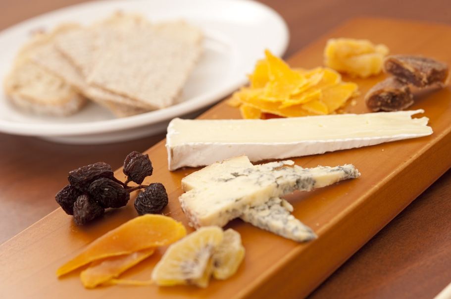 cheese platter; wooden cheese board, slices of cheeses