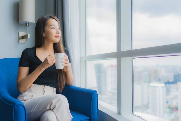 An image of a woman having her cup of coffee on her sofa.