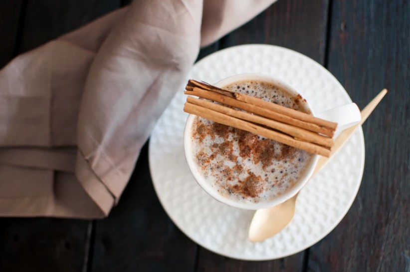 White ceramic mug on a saucer beside a beige plastic spoon