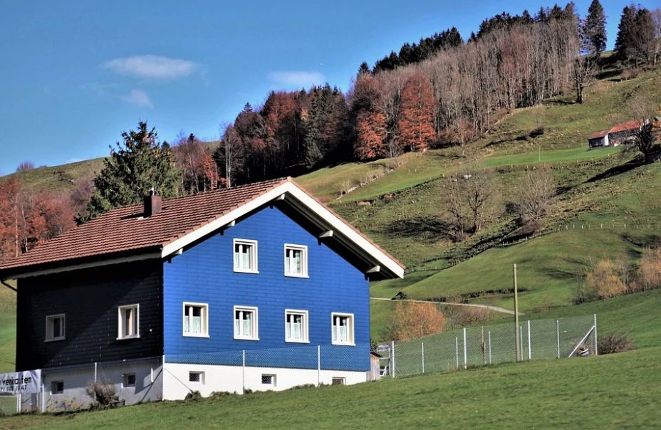A modern yet simple blue farmhouse in farmlands.