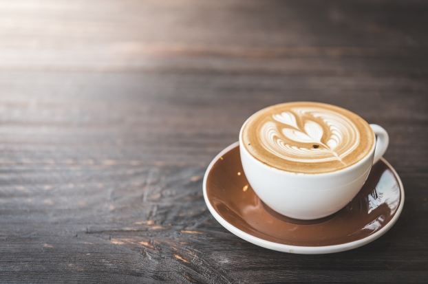 Image of a cup of coffee with latte art on a wooden table.