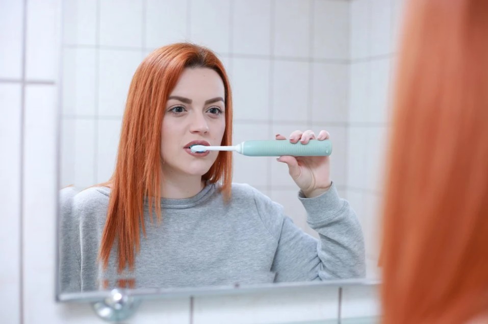girl brushing her teeth in the mirror