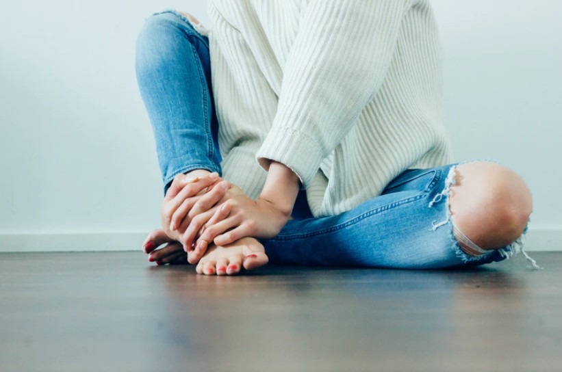woman holding her feet with her both hands