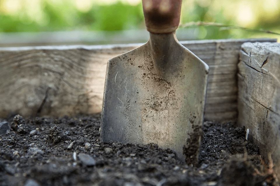 a spade and the soil inside a box garden