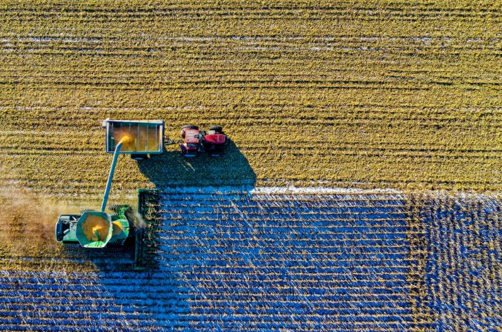 Two tractors in a vast field harvesting crops