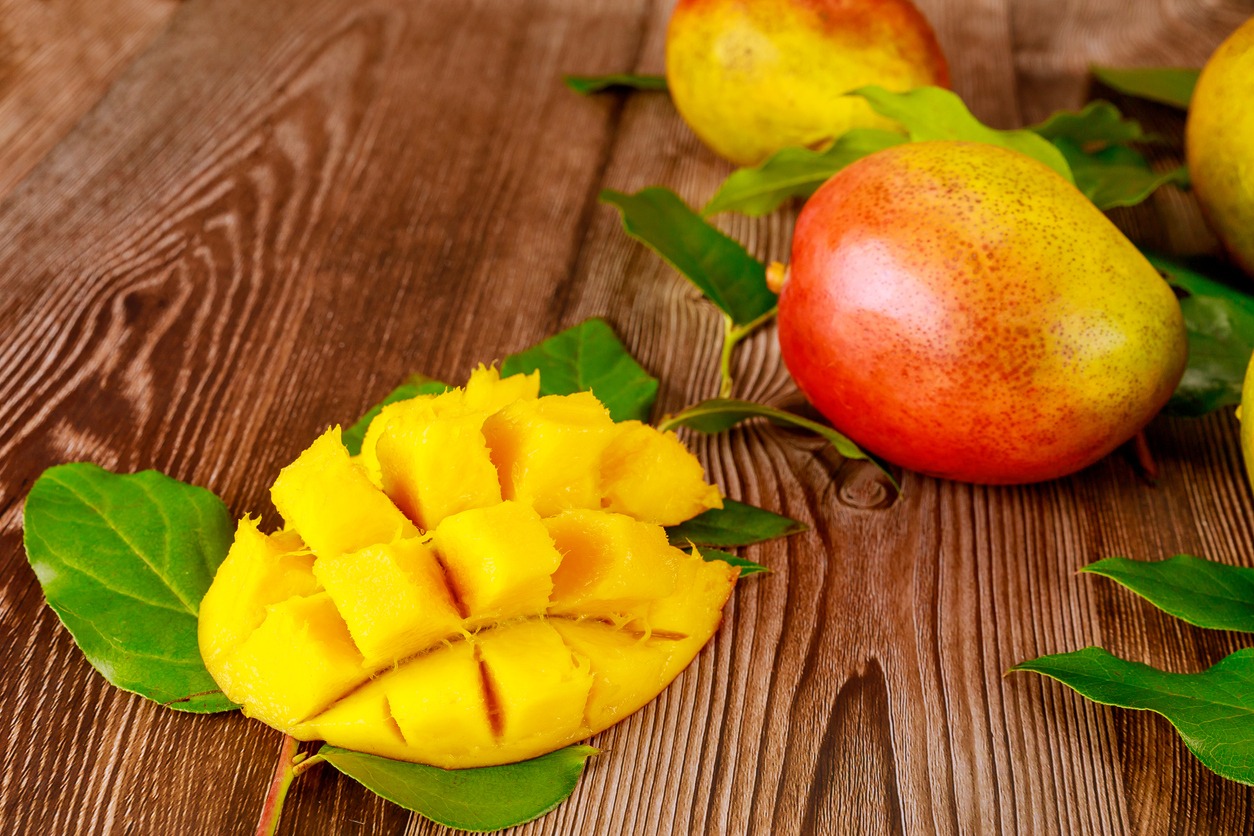 Delicious sweet mangoes on a wooden background.