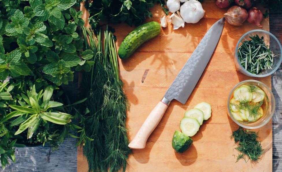 chopping board with knife and variety of herbs on it