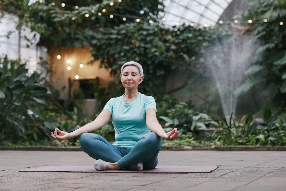 doing yoga on a mat with greens and fountain on background